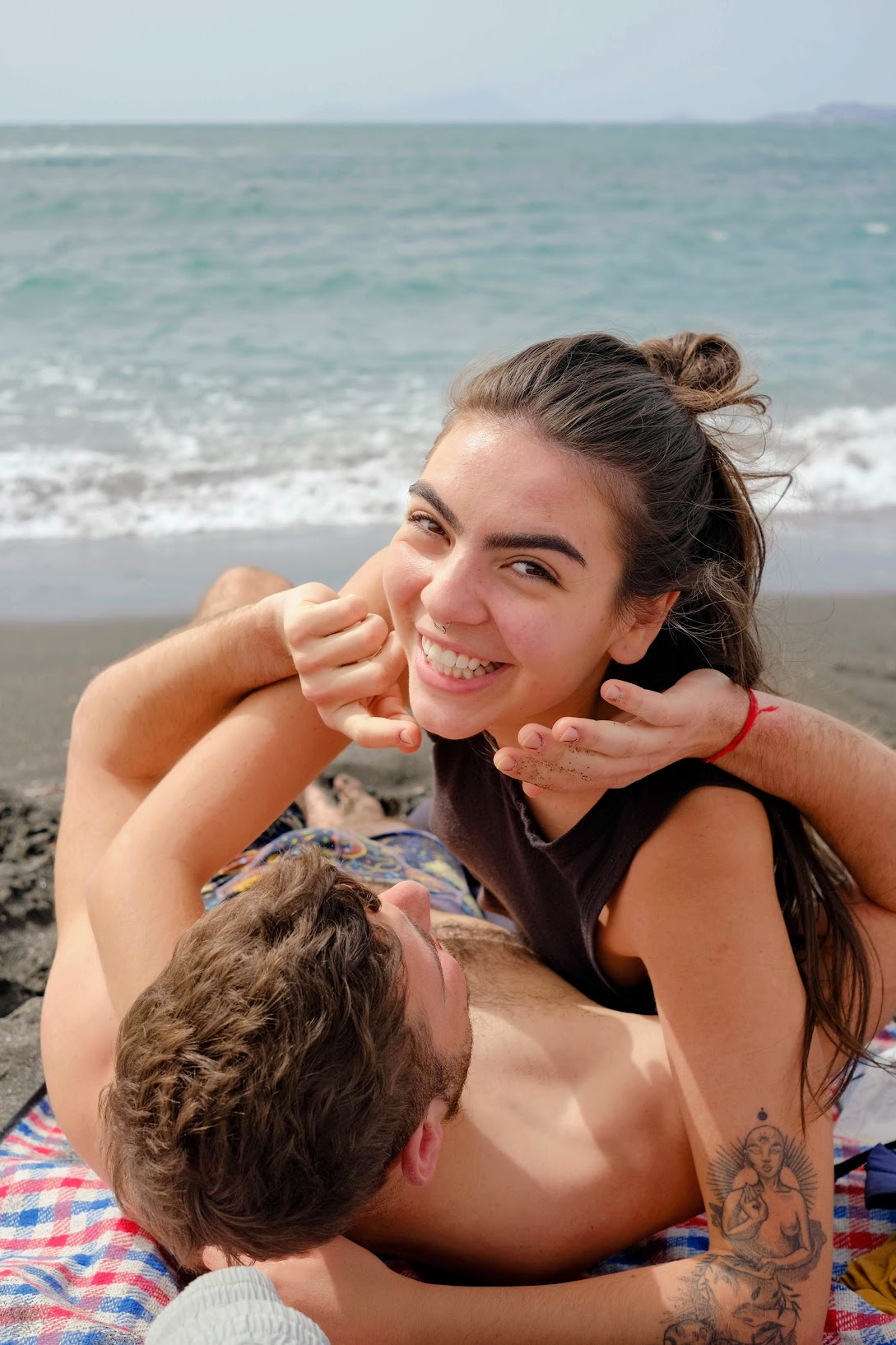 DSCF4699-EDIT Smiling woman lying on top of man at the beach with the ocean in the background